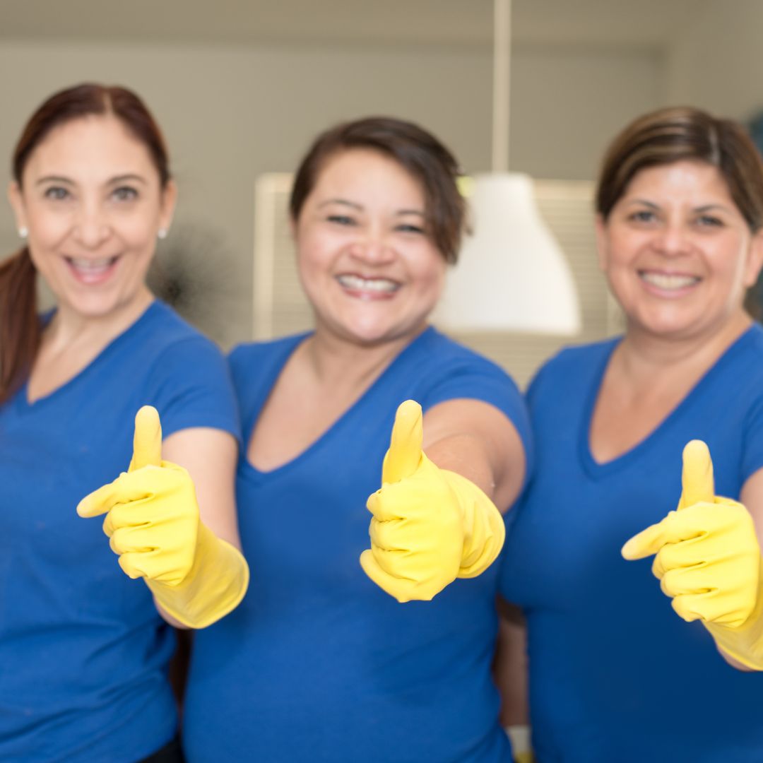 A team of vacate cleaners wearing blue shirts giving the thumbs up